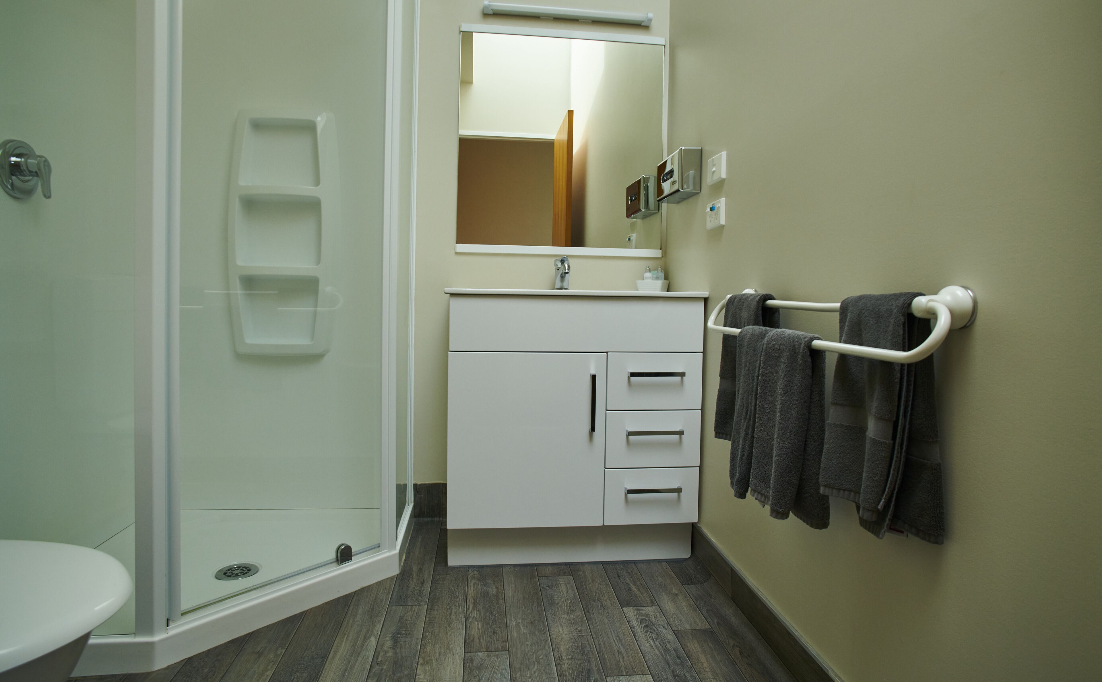 Een badkamer met douche, toilet, wastafel en handdoekhouder.