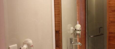 A bathroom with a white sink, a mirror, and a glass shower enclosure.