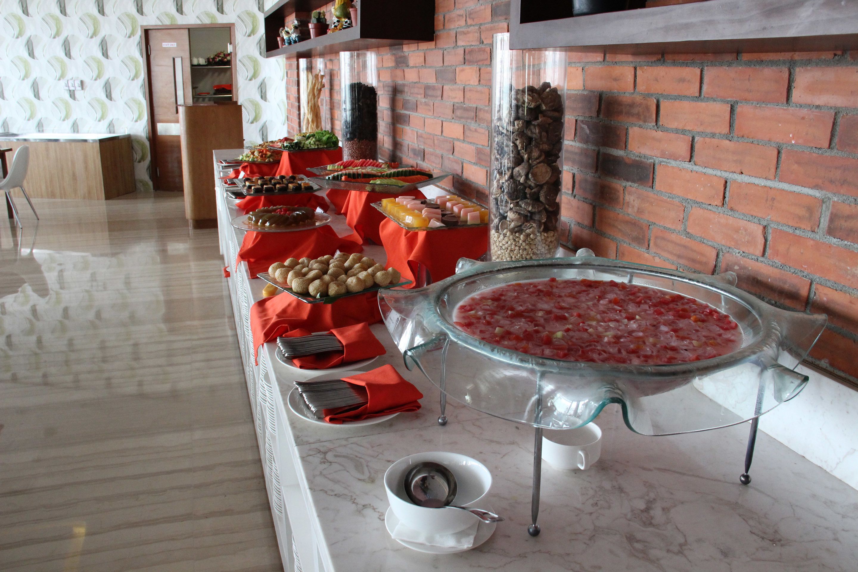 A buffet setup with various food items and a large glass punch bowl.