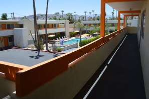 A hotel corridor with a pool area, palm trees, and a mountain view. - Musicland Hotel (Palm Springs)