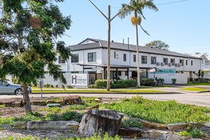 A two-story building with a sign for 'The Corner Homestead Motel' and a parking lot in front. - Ballina Homestead Motel (Ballina)