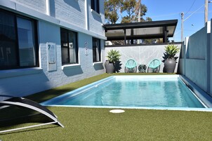 Una piscina al aire libre, sillones reclinables de piscina