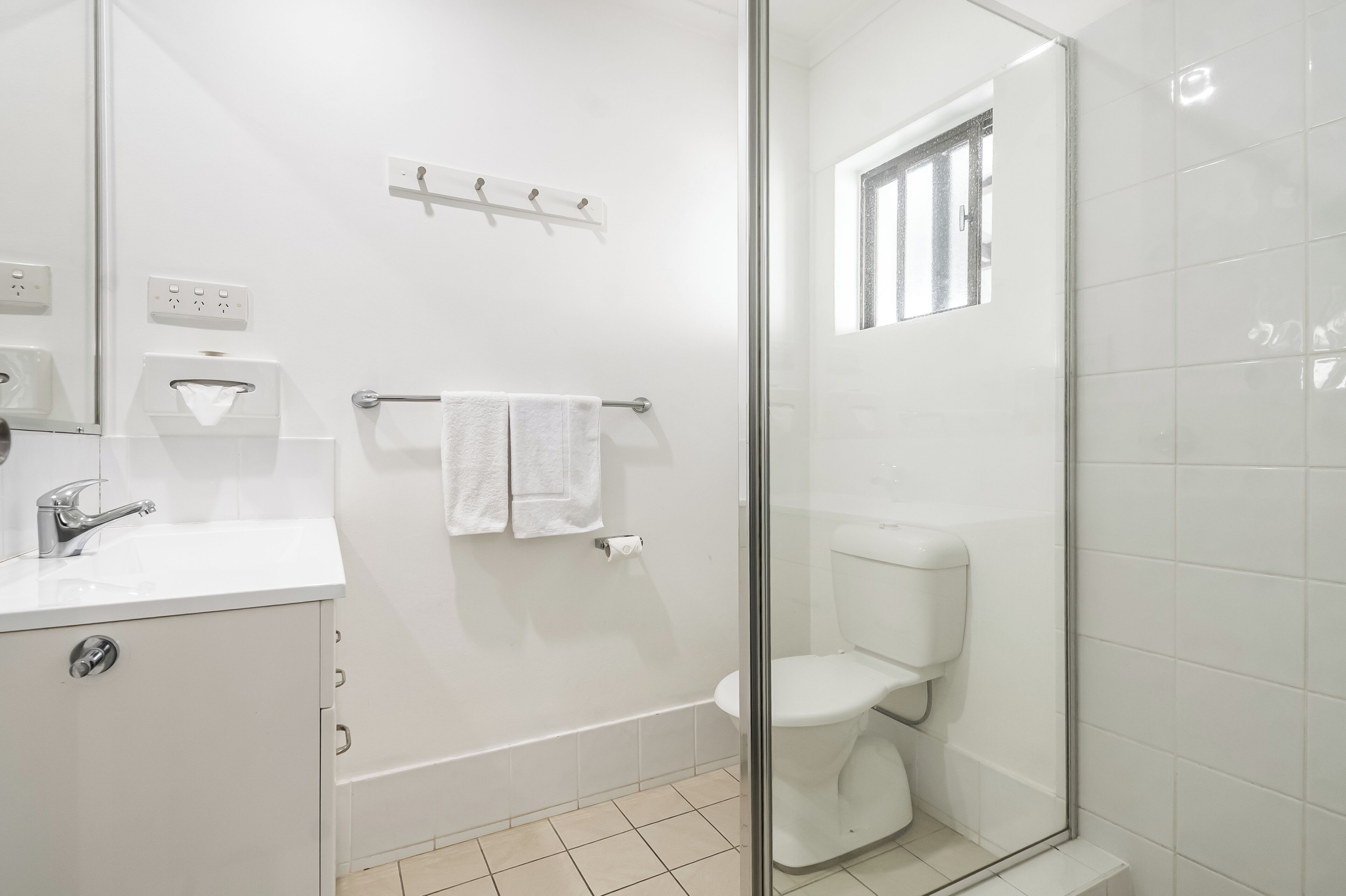 A modern bathroom with a glass shower enclosure, a white sink, and a toilet.
