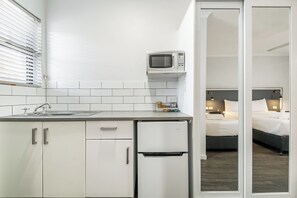 Une cuisine compacte équipée d’un four à micro-ondes, d’un évier et d’un petit réfrigérateur.
