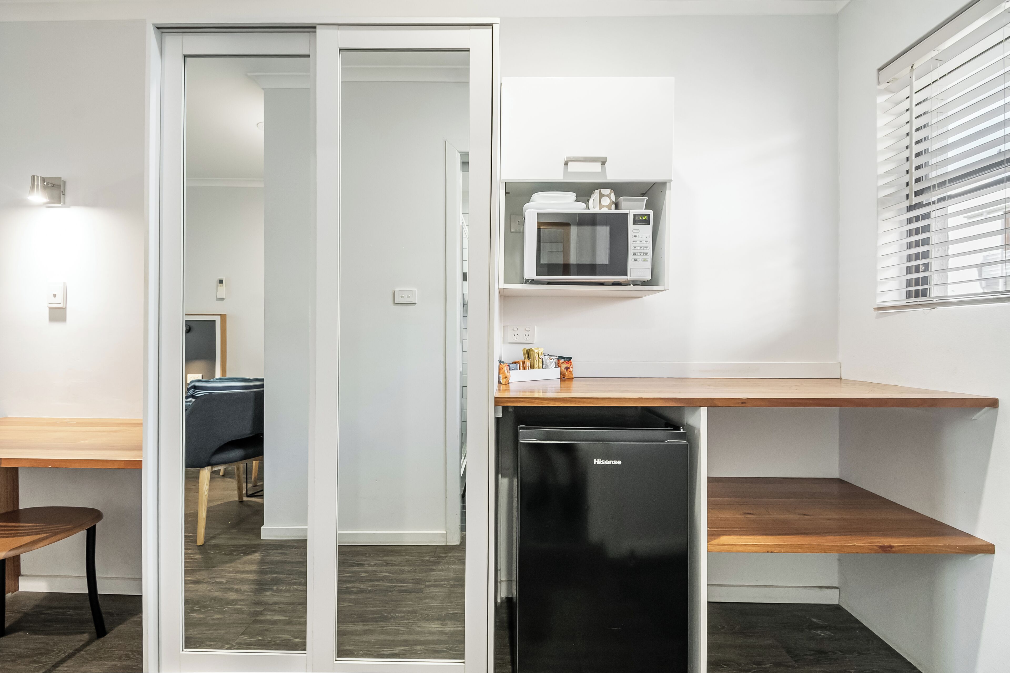 A compact kitchen with a microwave, a refrigerator, and a wooden countertop.