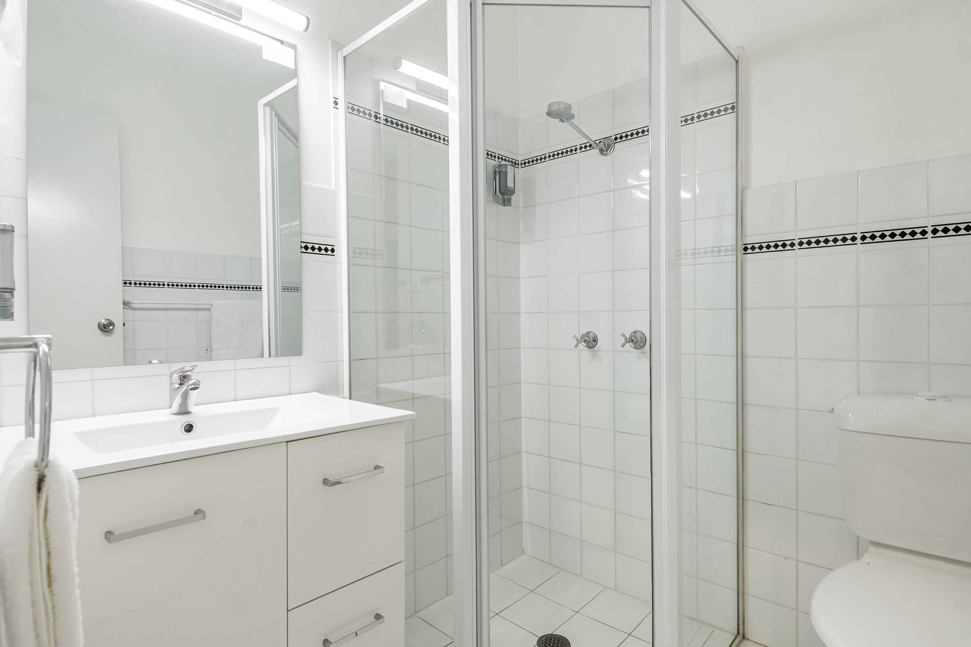 Une salle de bain avec un lavabo blanc, un miroir et une cabine de douche.