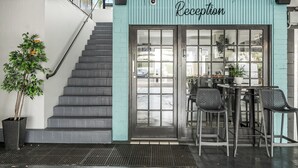 A reception area with a staircase, a potted plant, and a table with chairs. - Ballina Homestead Motel (Ballina)