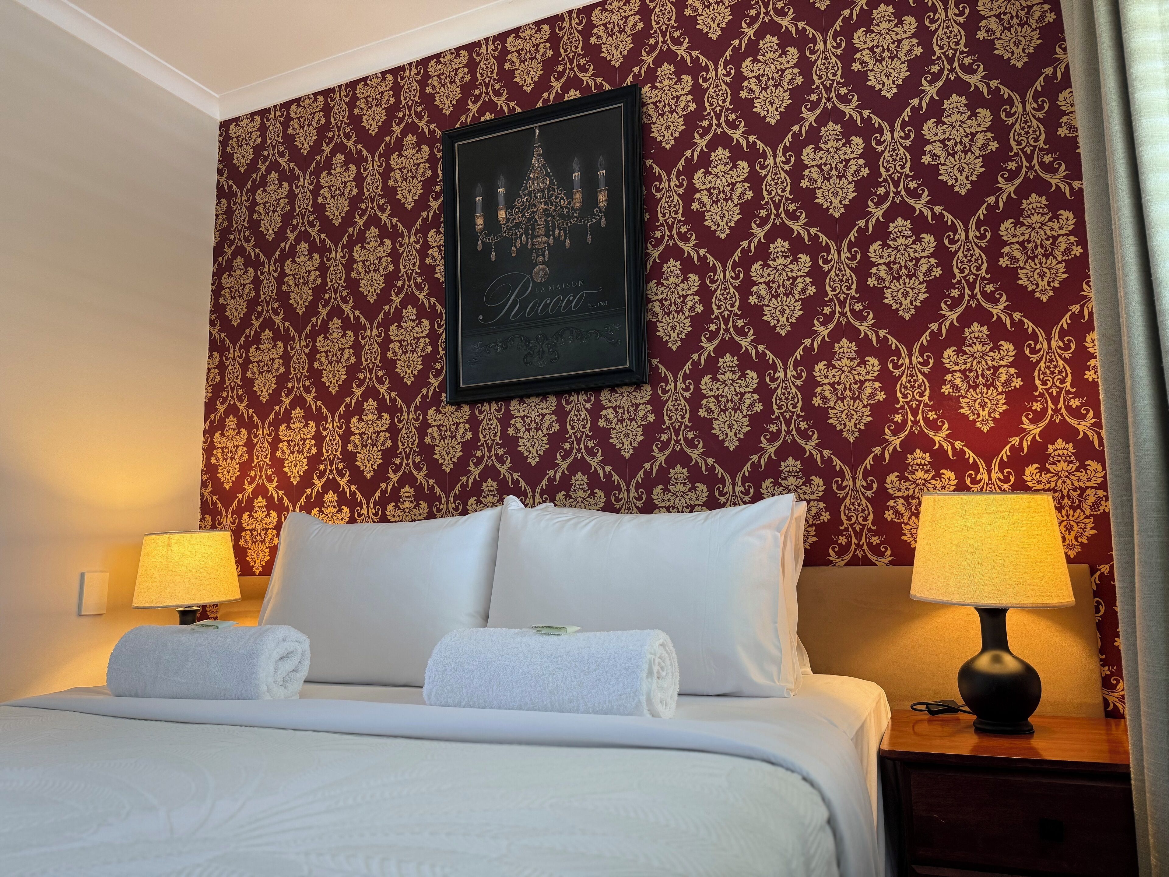 Una habitación de hotel con una cama grande, dos lámparas de noche y un cuadro en la pared.