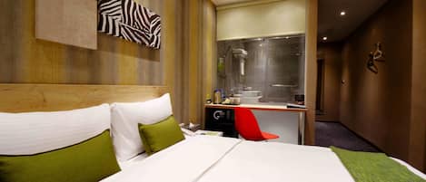 Habitación de hotel con una cama grande, un escritorio con una silla roja, ducha y espejo.