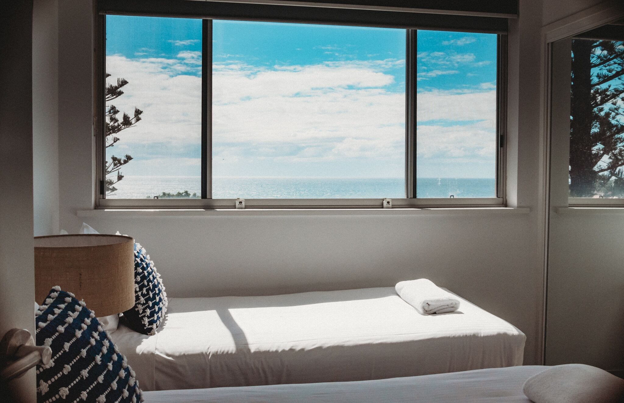 Ein Schlafzimmer mit großem Fenster, einem Bett, einer Lampe und Meerblick.