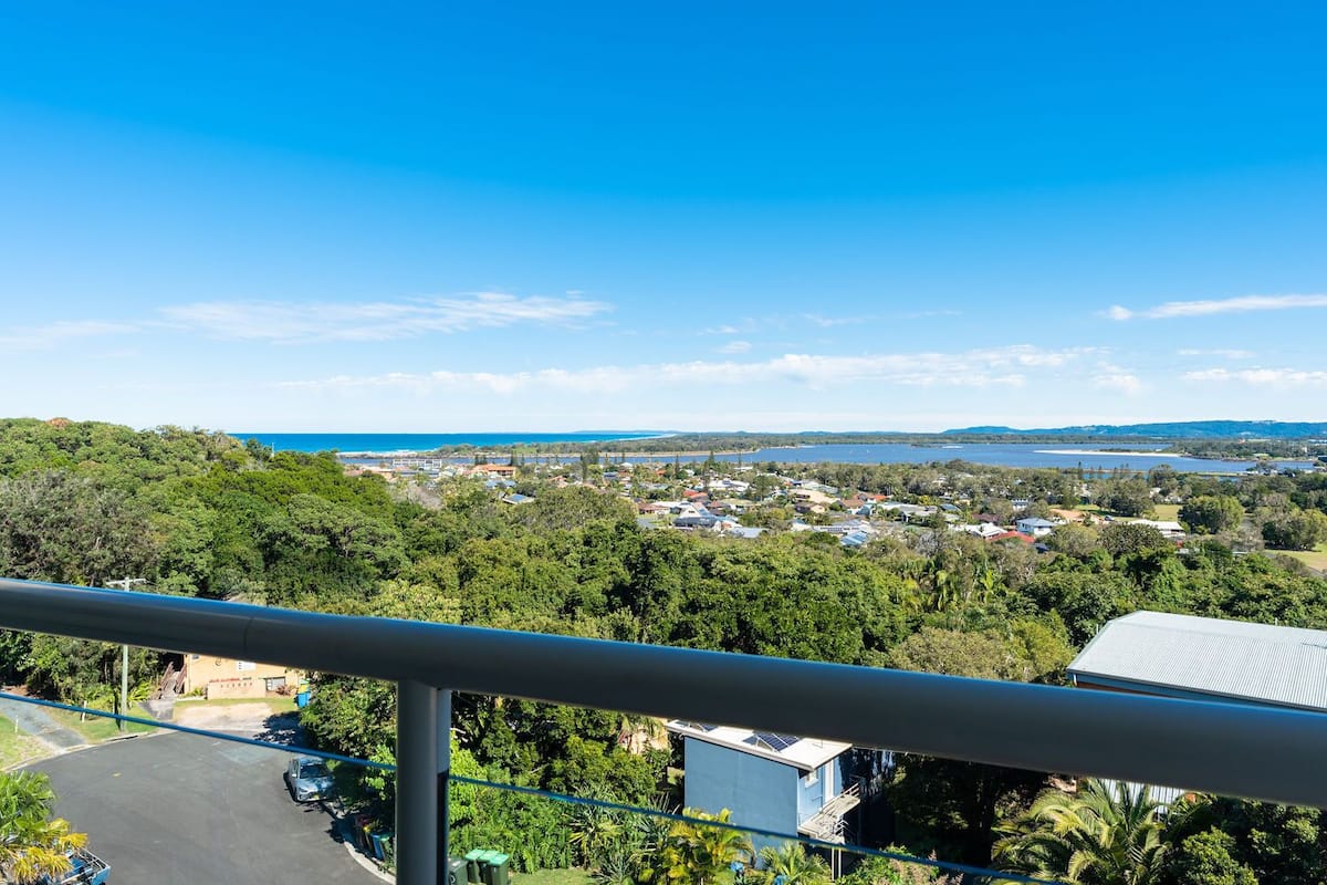 A coastal residential area with houses, a clear blue sky, and a view of the sea.