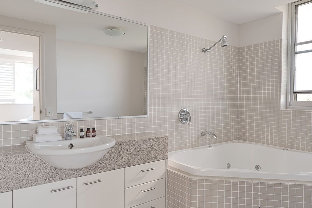 Een moderne badkamer met een vrijstaand bad, een wastafel met spiegel erboven en een raam voor natuurlijk licht.