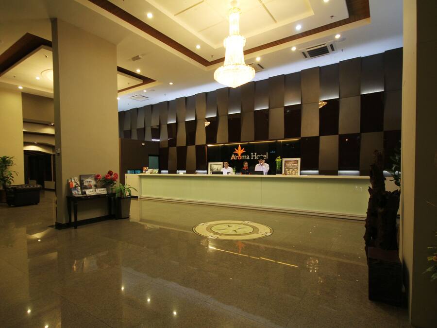 A hotel reception area with a modern design, featuring a reception desk, a chandelier, and a check-in counter.
