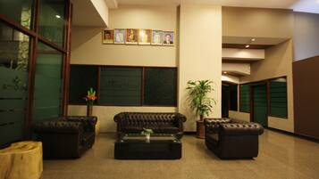A lobby with a leather sofa, a coffee table, and a potted plant.