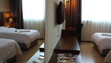 A hotel room with two beds, a TV mounted on the wall, and a desk with magazines.