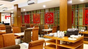 A restaurant interior with multiple tables and chairs, wooden beams, and red decorative panels.