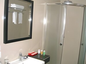 Une salle de bain équipée d’un lavabo, d’un miroir et d’une douche à parois en verre.