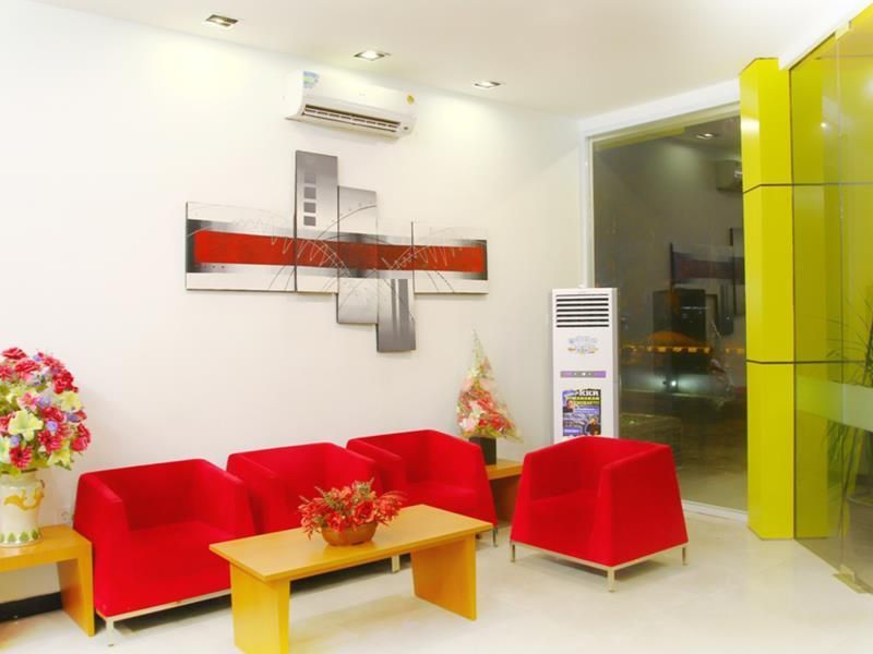 A reception area with a red sofa set, a wooden table, and a potted plant.