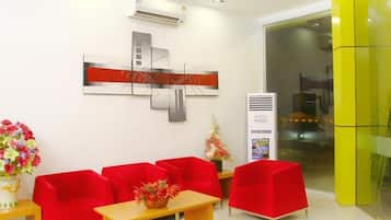 A reception area with a red sofa set, a wooden table, and a potted plant.