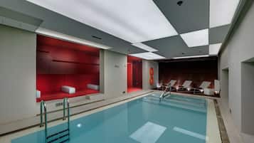 An indoor swimming pool with a red seating area, a lifeguard stand, and a sunroof.