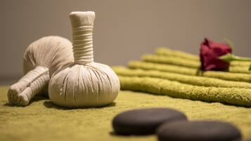 A massage stone, a rose, and a towel on a textured surface.