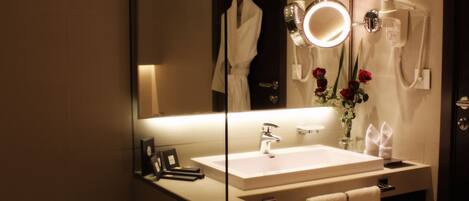A modern bathroom with a large mirror, a sink, a bathtub, and a vanity with a towel rack.