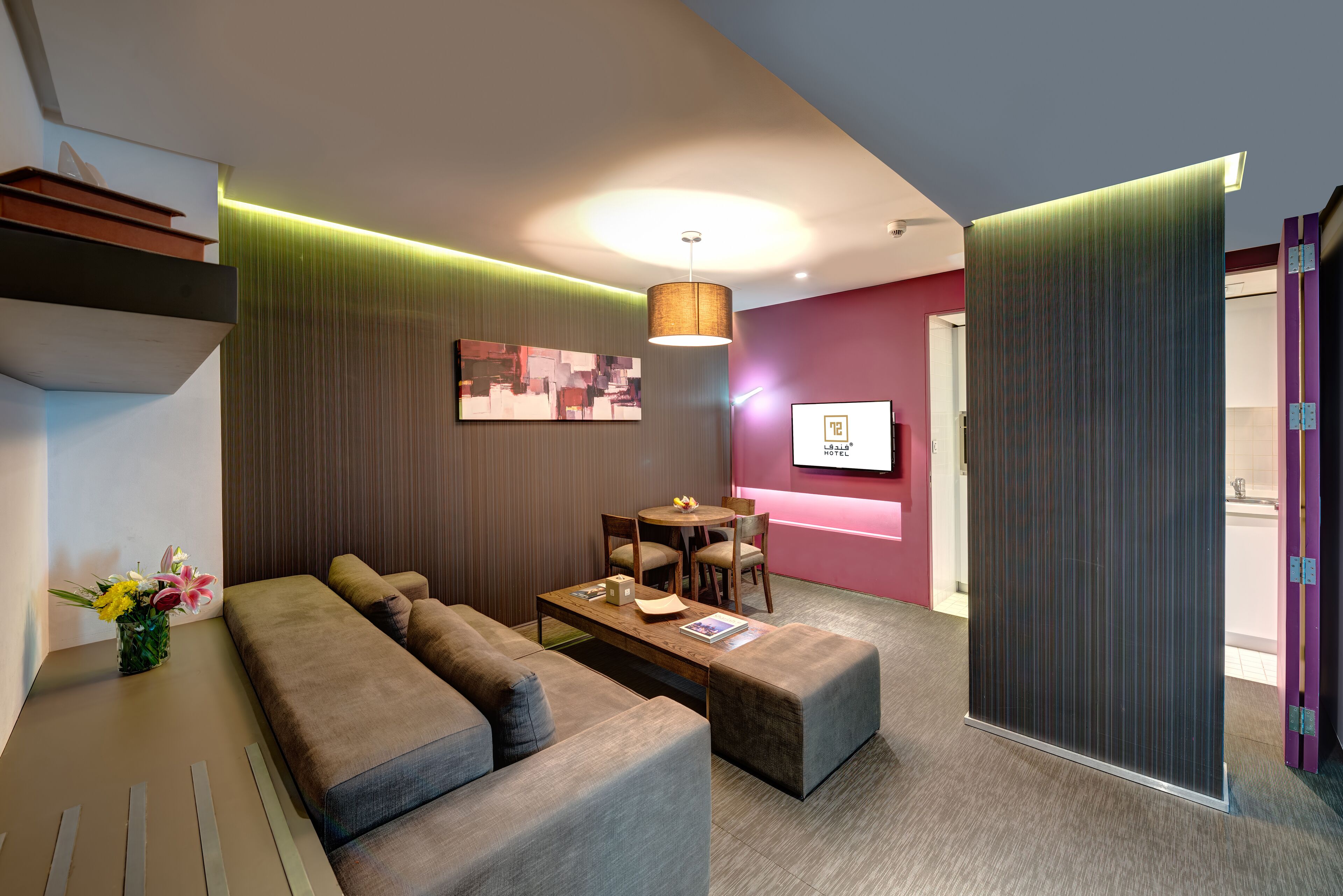 A modern hotel room with a sofa, ottoman, and a small dining table.