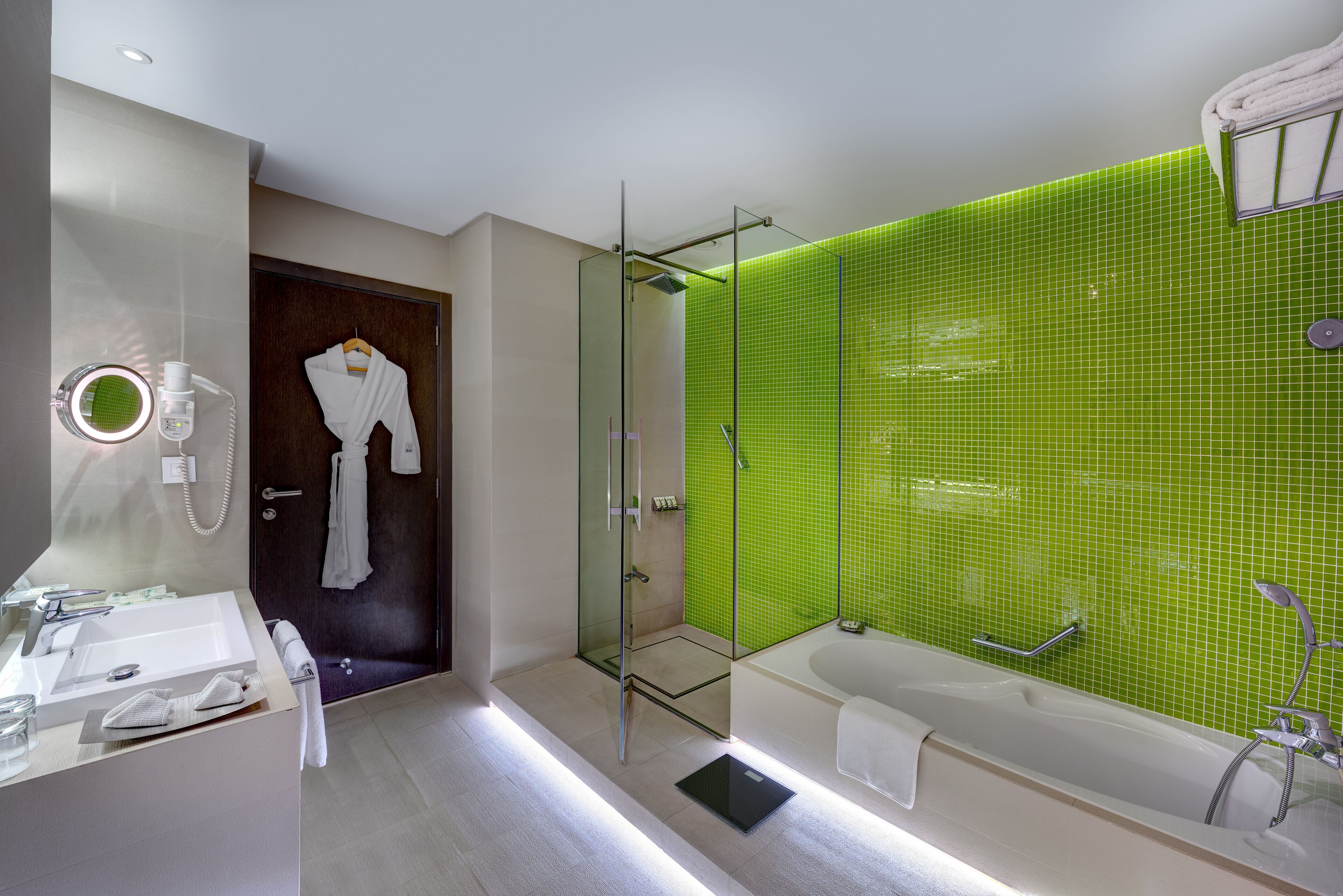 Une salle de bain moderne dotée d’une douche à parois de verre, d’une grande baignoire et d’un meuble-lavabo avec un miroir et un évier.