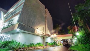A modern hotel with a prominent corner building, a well-lit entrance, and lush greenery around. - Sahid Kawanua Manado (Manado)