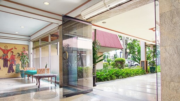 A lobby with a glass door entrance, a mural, a table with chairs, and a garden view. - Sahid Kawanua Manado (Manado)