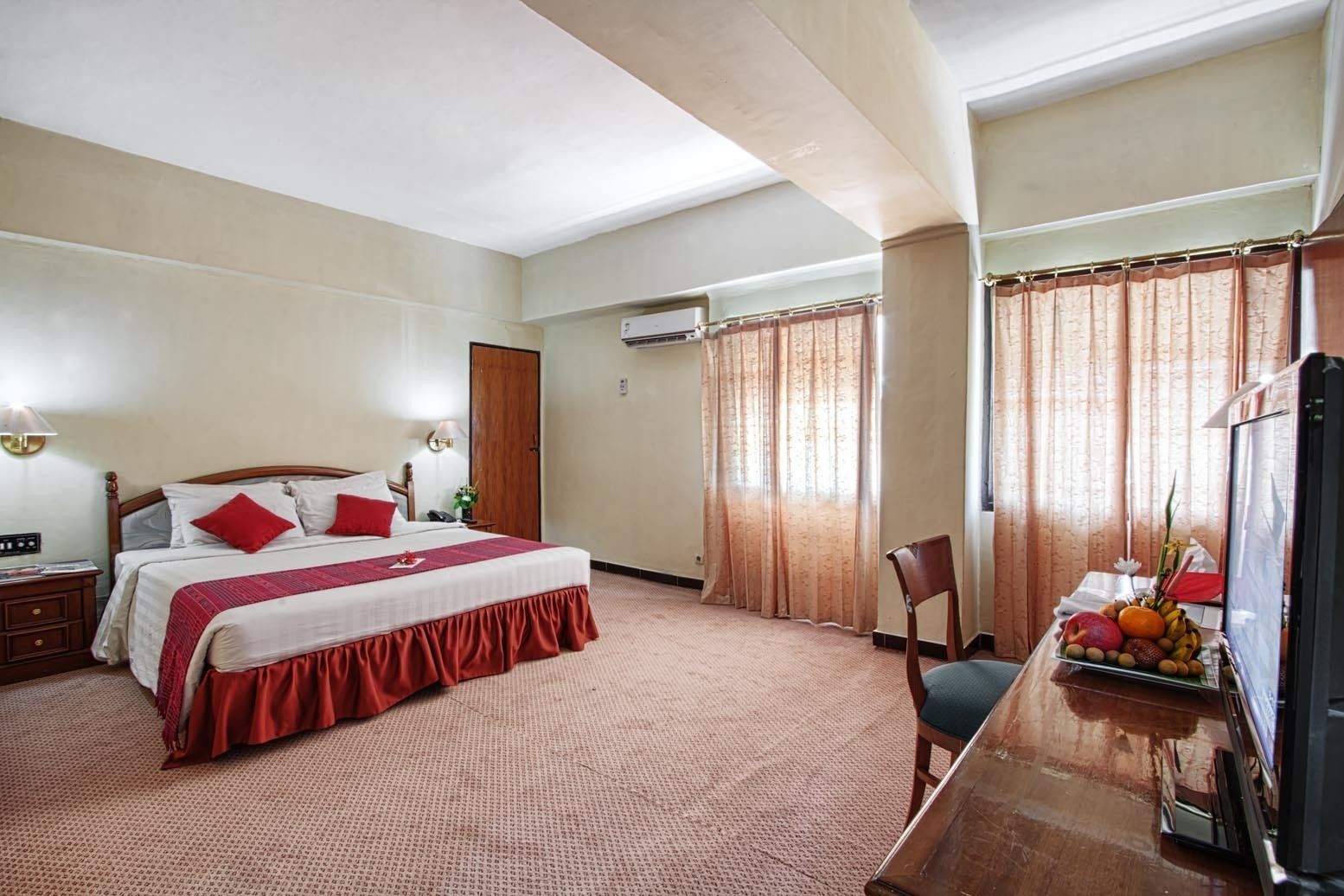 Quarto de hotel com uma cama grande, uma escrivaninha com um computador e uma cadeira.