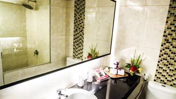 A modern bathroom with a large mirror, a white sink, and a toilet.