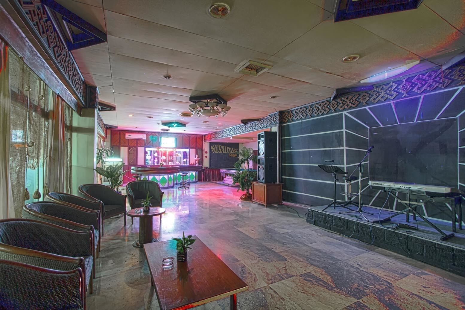Un vestíbulo con mostrador de recepción, zona de estar y escenario con equipo de sonido.