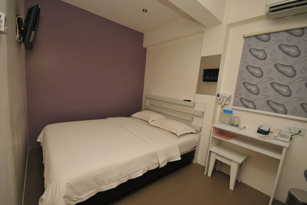 Quarto de hotel com cama, escrivaninha e cadeira.