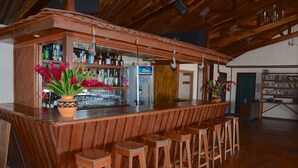 Zona de bar con taburetes de madera, una barra y un refrigerador.