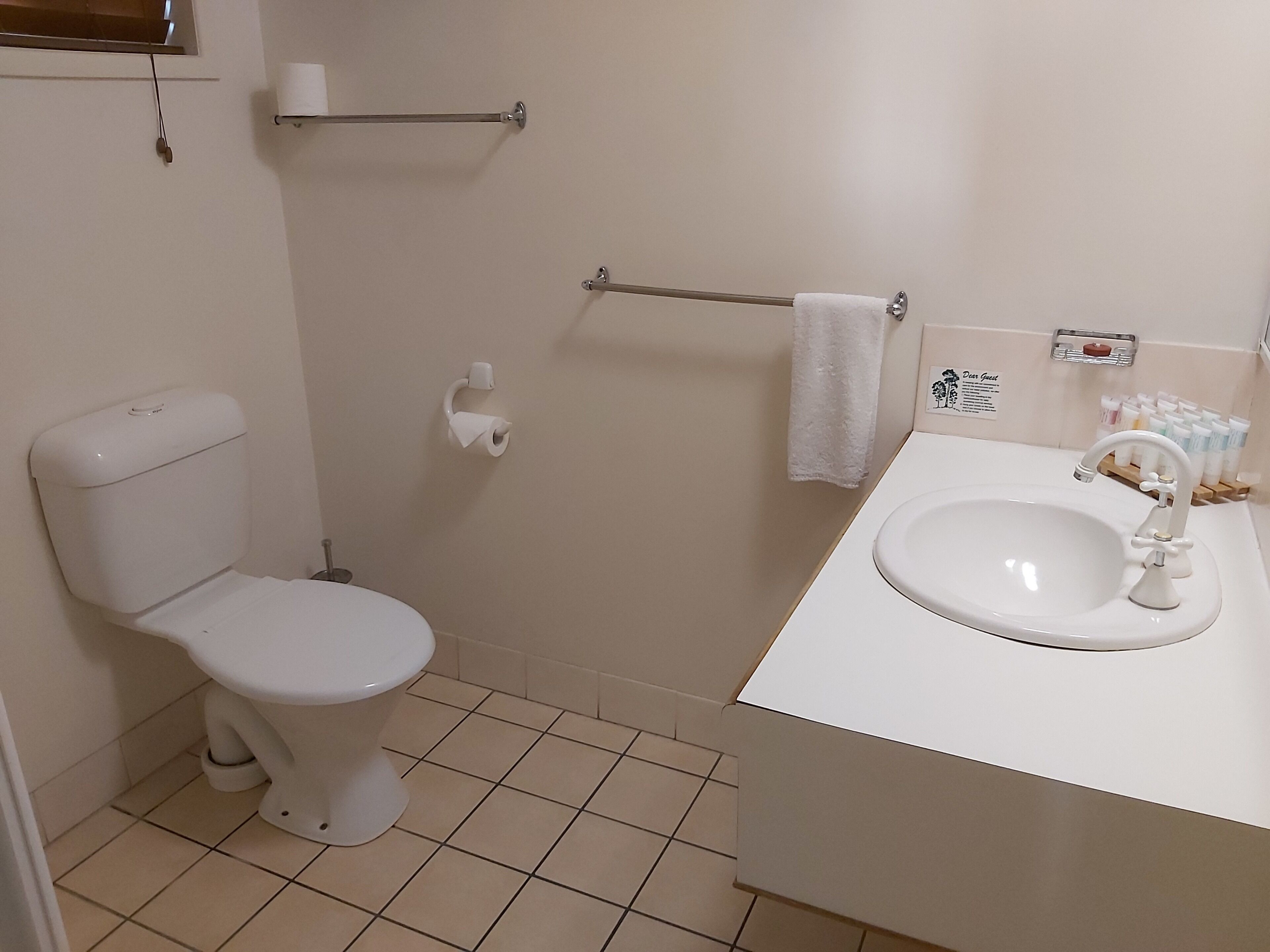Une petite salle de bain propre, équipée de toilettes, d’un lavabo et d’un espace douche.