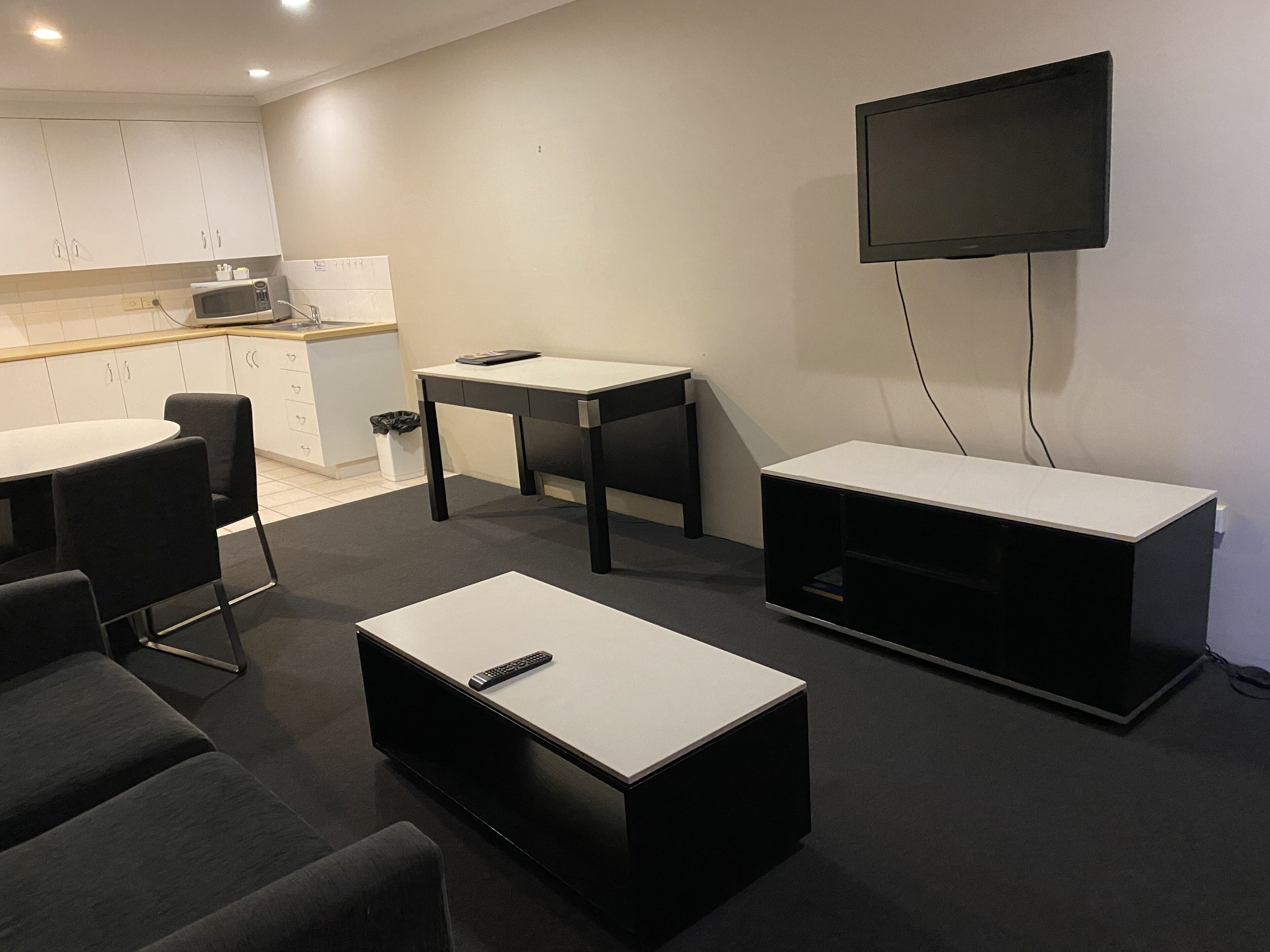 Un salon moderne avec un téléviseur à écran plat, une table basse, un canapé et une petite table.