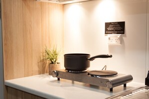 A modern kitchen with a portable stove, a potted plant, and a sign on the wall.