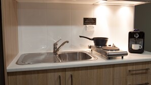 Una cocina moderna con un lavaplatos de acero inoxidable, una estufa y una cafetera.