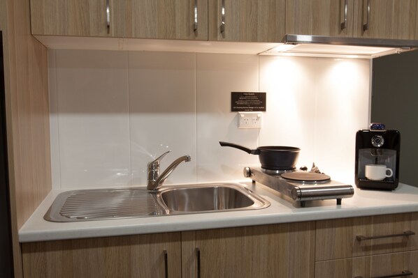 A modern kitchen with a stainless steel sink, a stove, and a coffee machine.