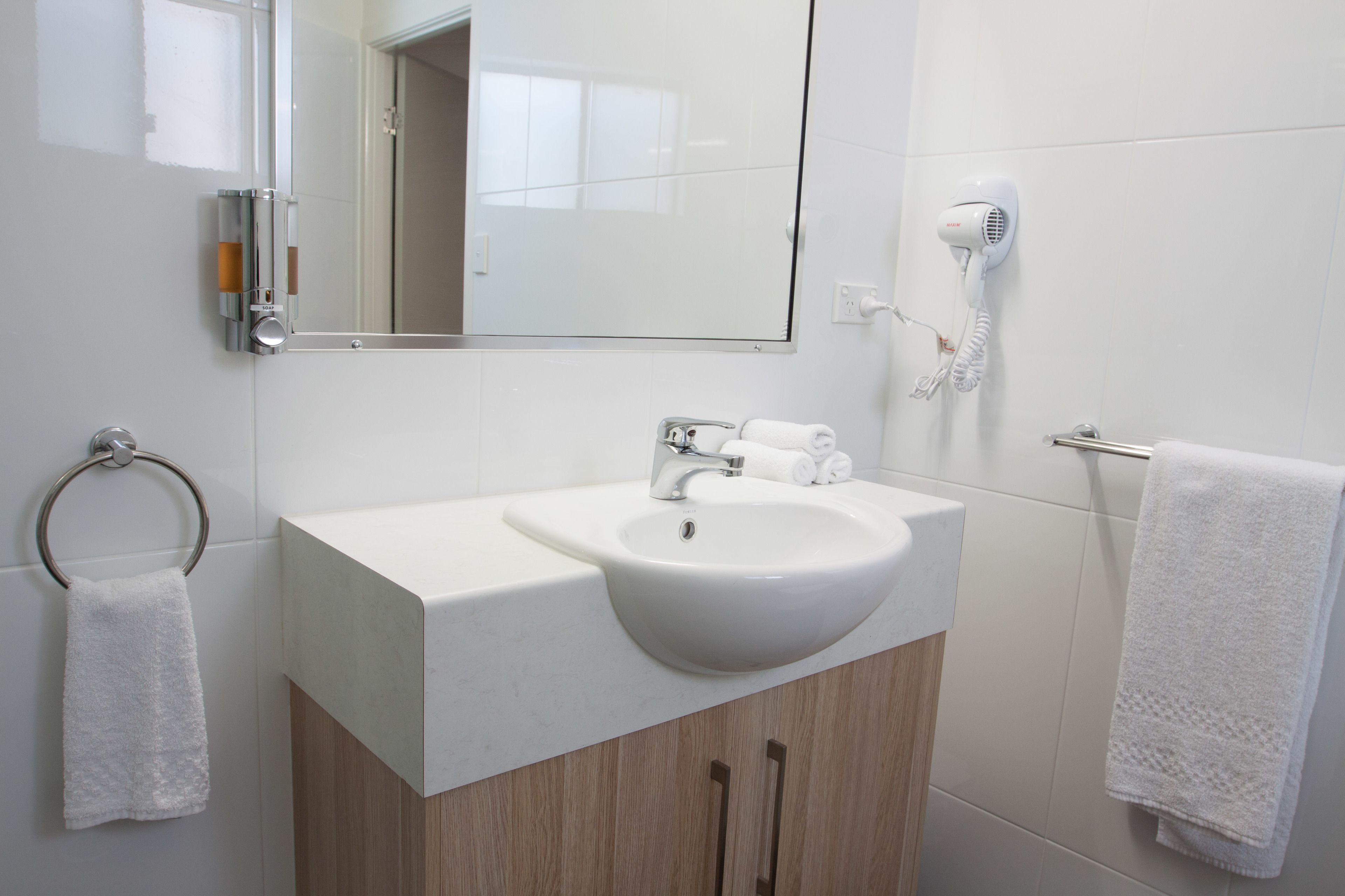 A bathroom with a white sink, a mirror, a towel rack, and a hairdryer.