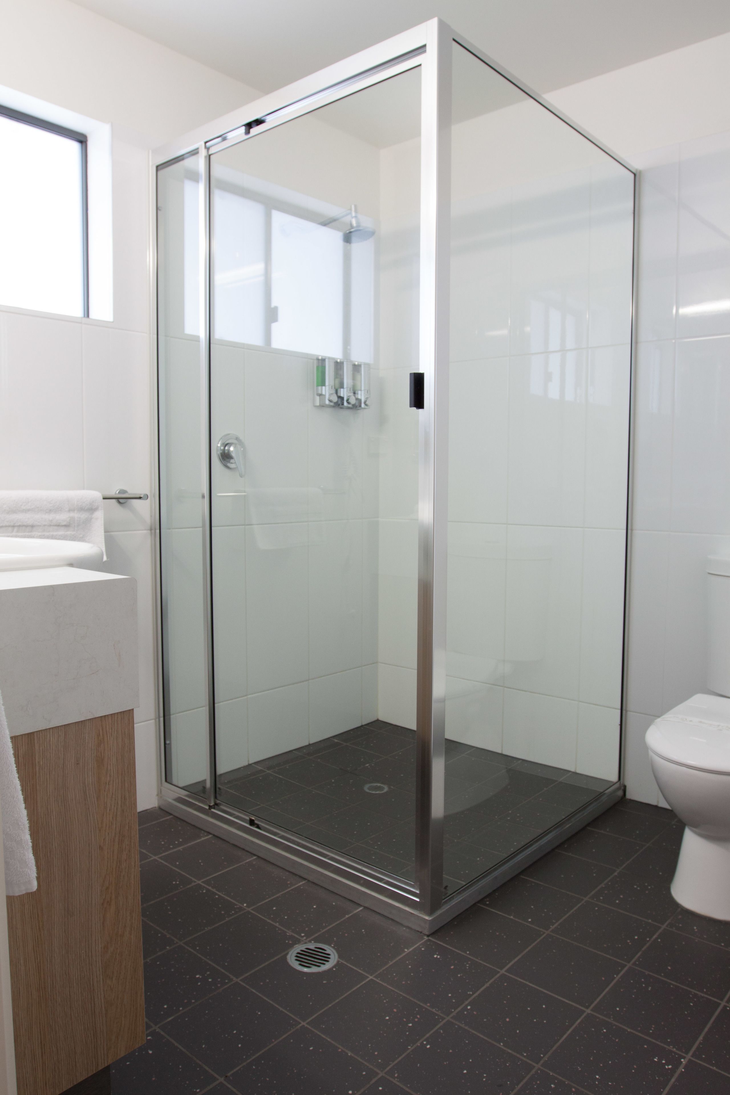 A modern bathroom with a glass-enclosed shower, a white toilet, and a sink with a wooden countertop.