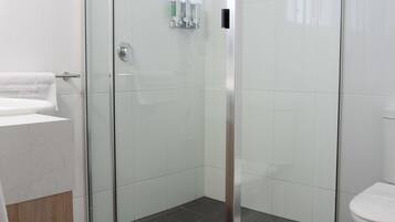 A modern bathroom with a glass-enclosed shower, a white toilet, and a sink with a wooden countertop.