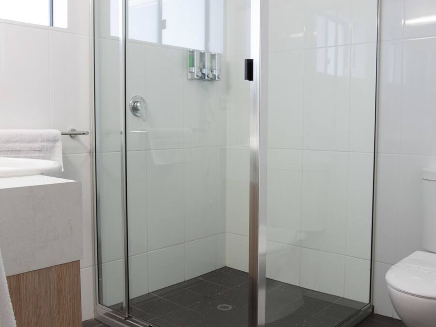 A modern bathroom with a glass-enclosed shower, a white toilet, and a sink with a wooden countertop.