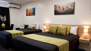 Habitación de hotel con dos camas, un escritorio y una silla. Hay cuadros en las paredes y una lámpara en la mesita de noche.