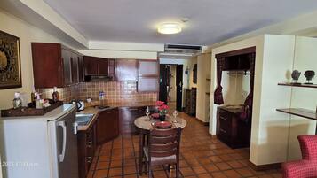 A modern kitchen with dark wooden cabinets, a tiled backsplash, and a central island with a vase of flowers.