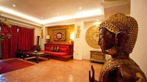 Une pièce avec un canapé rouge, une table basse et une statue de Bouddha.