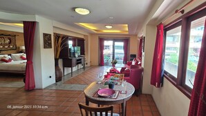 Un coin repas avec une table dressée pour quatre personnes, un canapé et un téléviseur en arrière-plan.