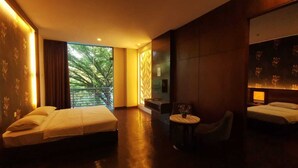 A hotel room with two beds, a small round table, a chair, and a balcony with a view of trees. - WaterFront Boutique Hotel (Port Dickson)