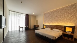 A hotel room with a large bed, bedside tables with lamps, a desk, and a chair. - WaterFront Boutique Hotel (Port Dickson)